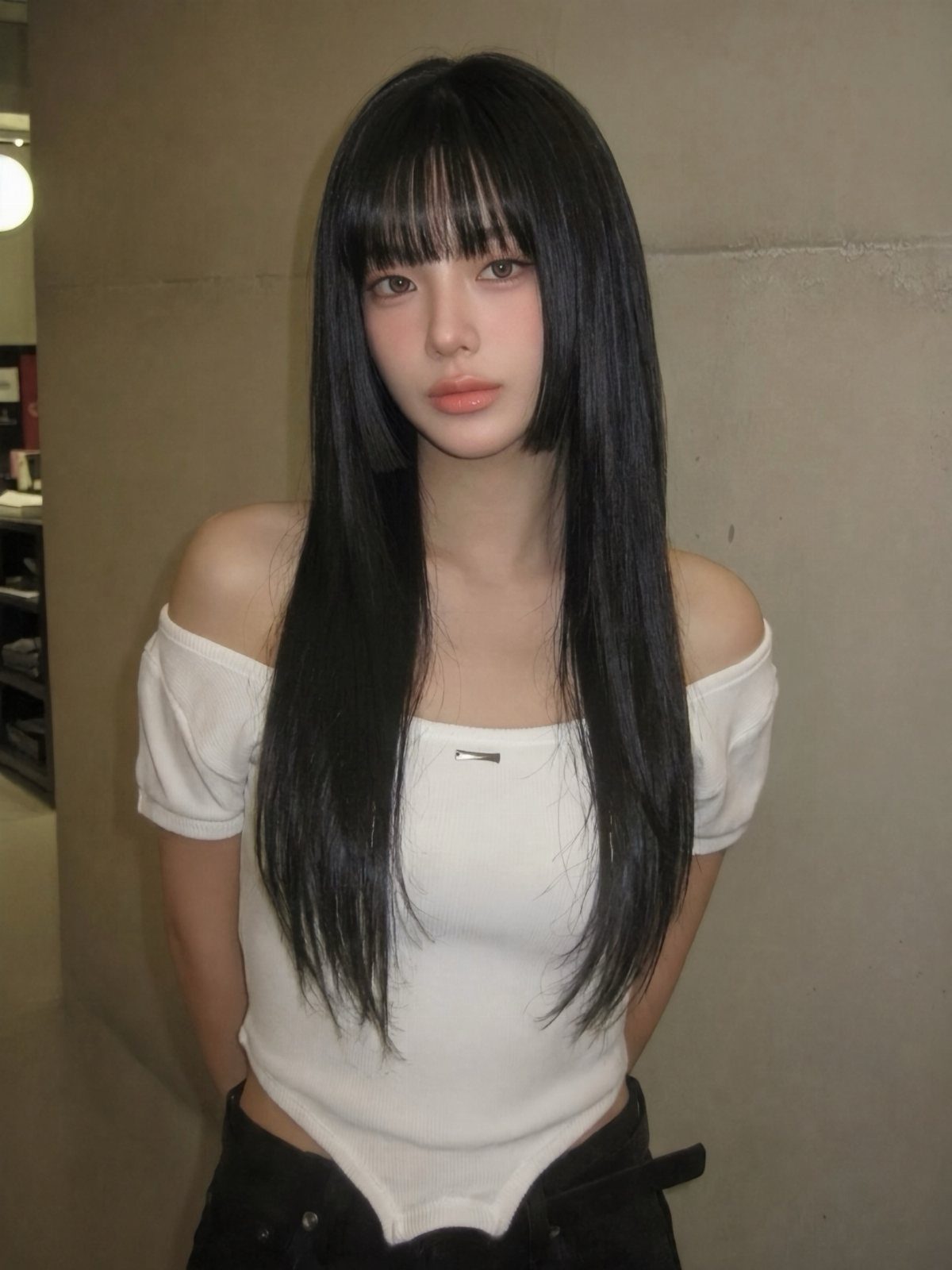 Woman models long straight black hair with blunt bangs and short side pieces