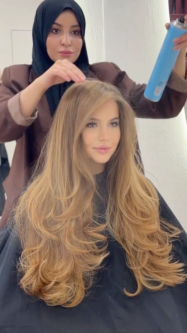Long blonde hair with chest-length front sections blending into longer, voluminous layers