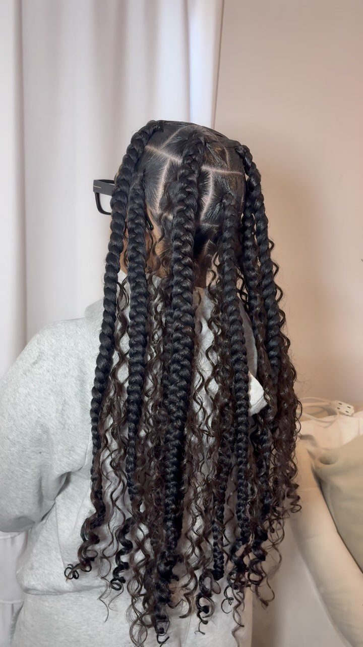 Long dark box braids with loose curly tendrils cascading down the back
