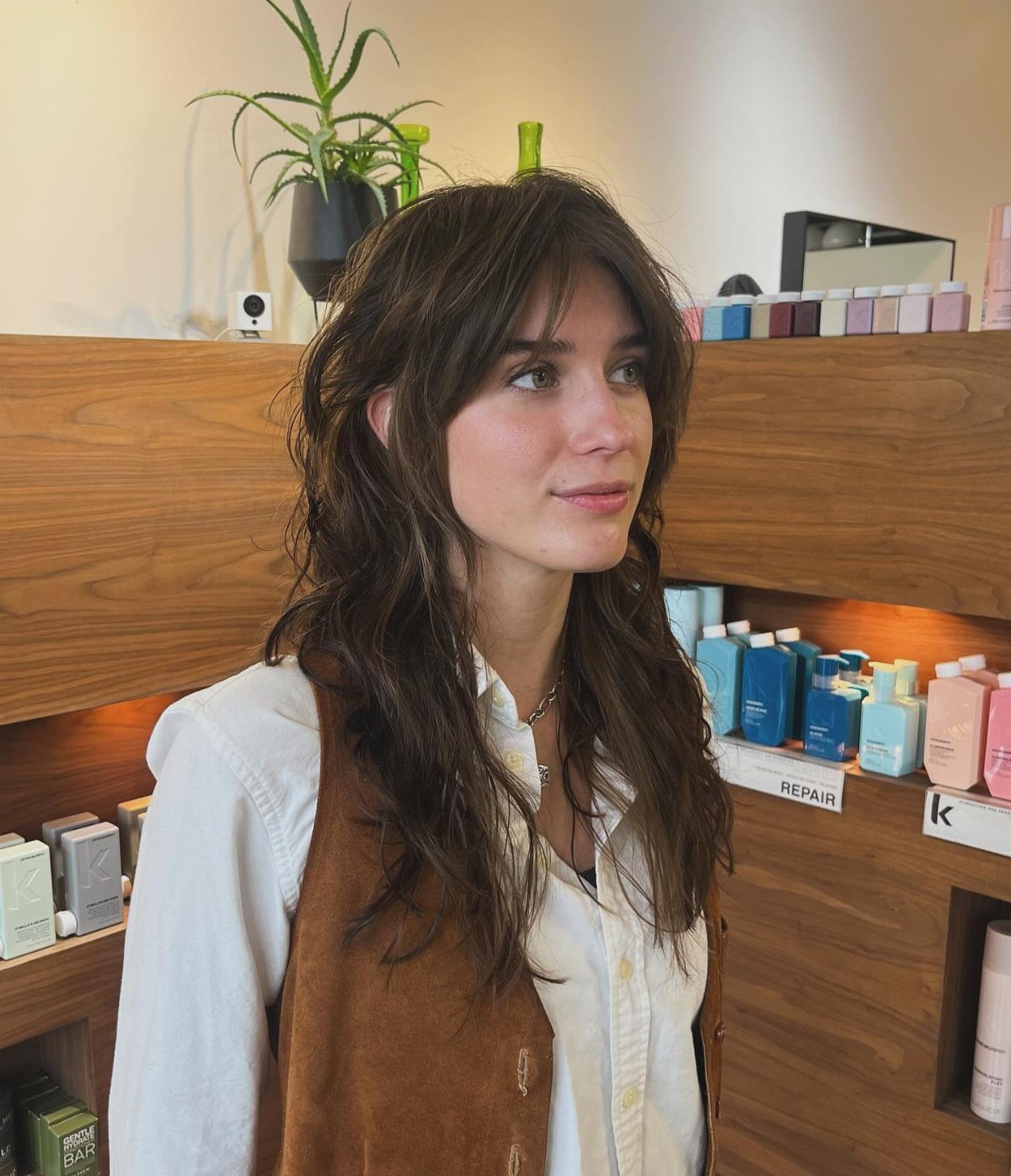 Woman with long dark shaggy layers and wispy bangs in a shop