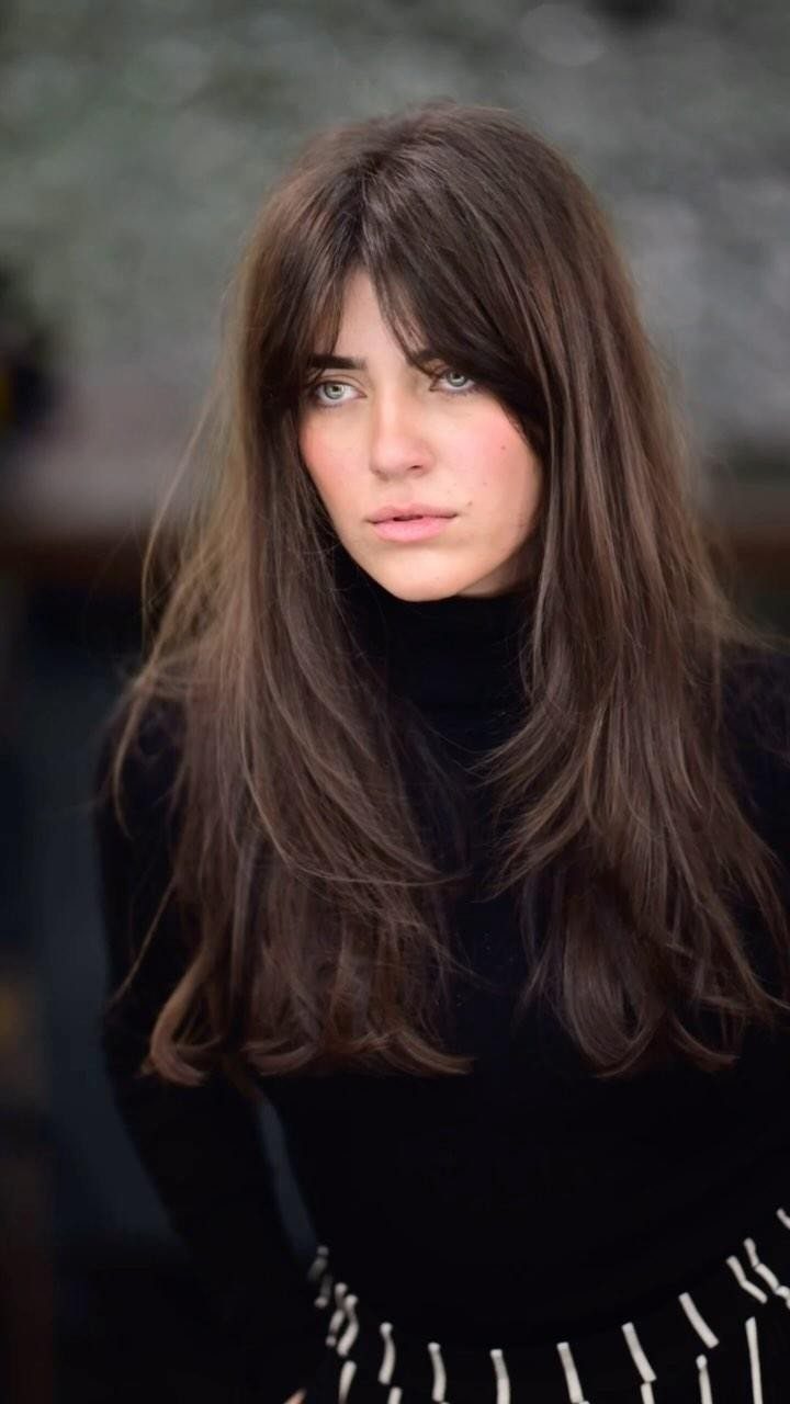 Woman with long brown hair and sweeping side bangs framing her face