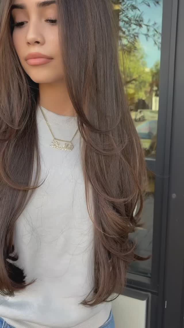 Woman showing long, side-parted brown hair with smooth cascading layers
