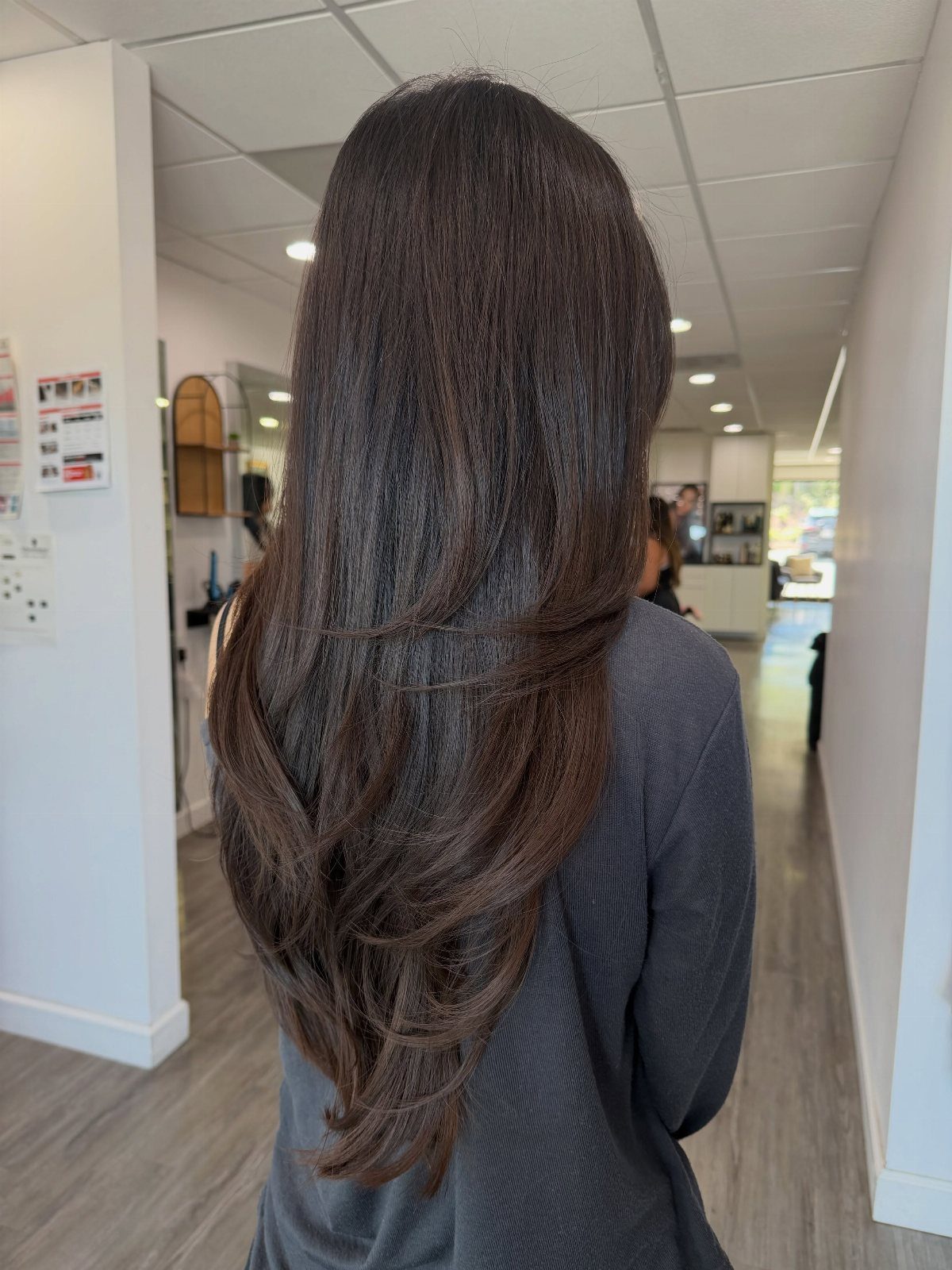 Long dark layered hair descends into a pointed V shape at the back