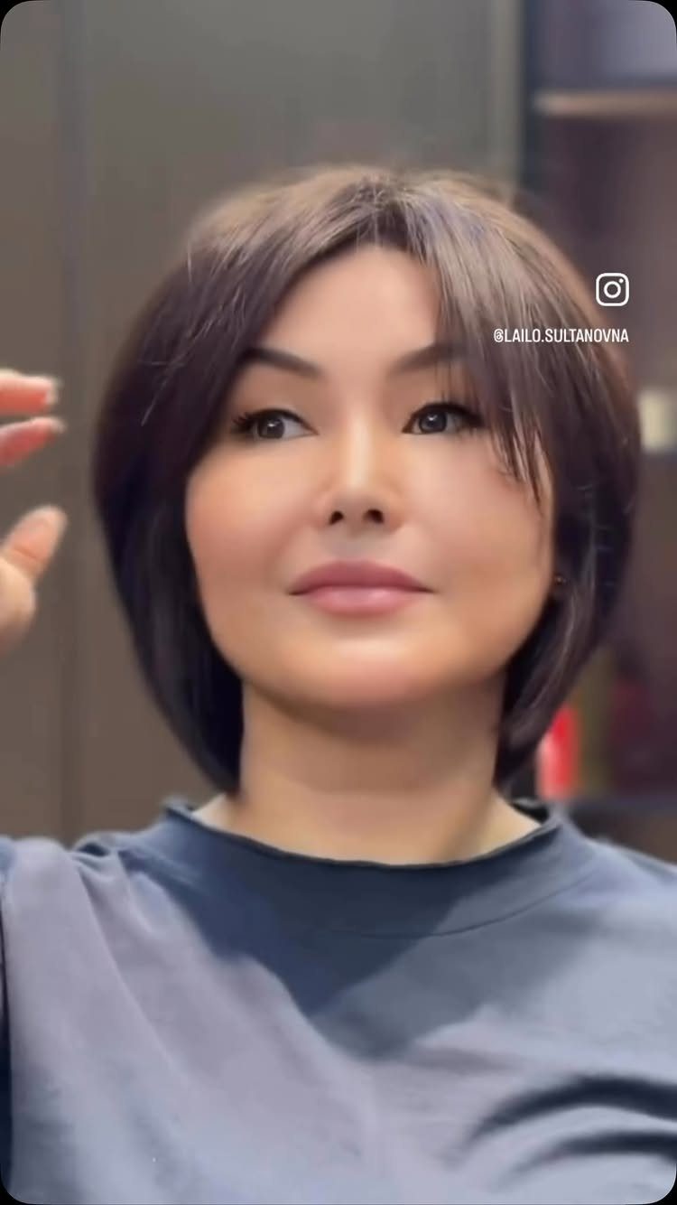 Woman displaying a dark brown angled bob with wispy bangs in a salon