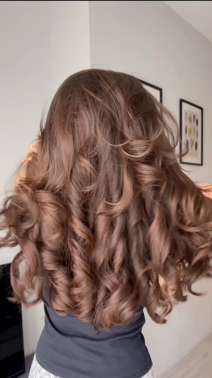 Long, glossy brown hair styled in a voluminous bouncy blowout with loose curls
