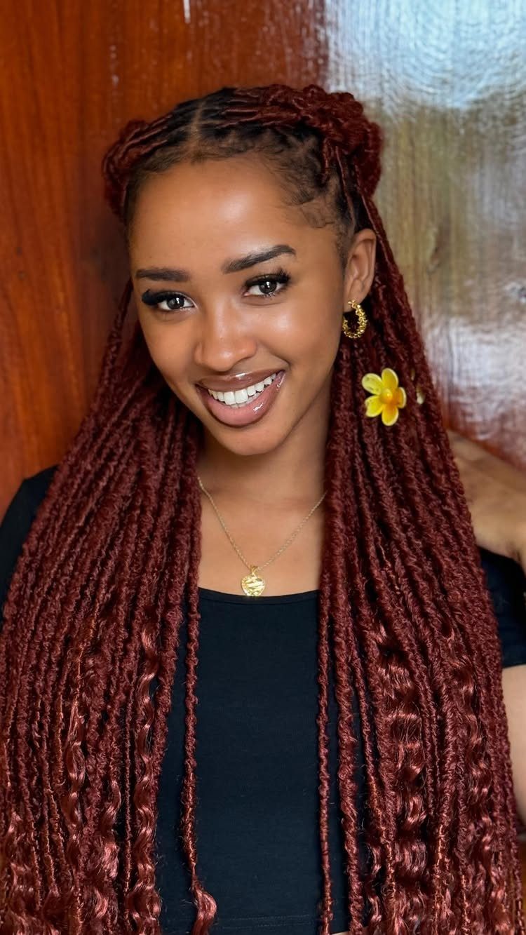 Woman with long burgundy-red braids and a braided crown smiles