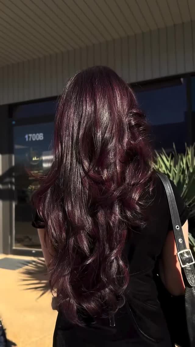 Long, glossy cherry-red waves fall down a person's back