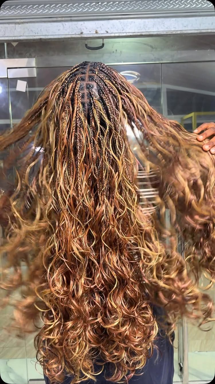 Long copper-brown curls are held out at the ends beneath a salon hood.