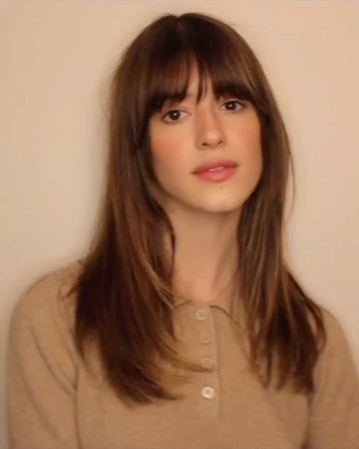 Woman with long layered brown hair and short wispy fringe bangs