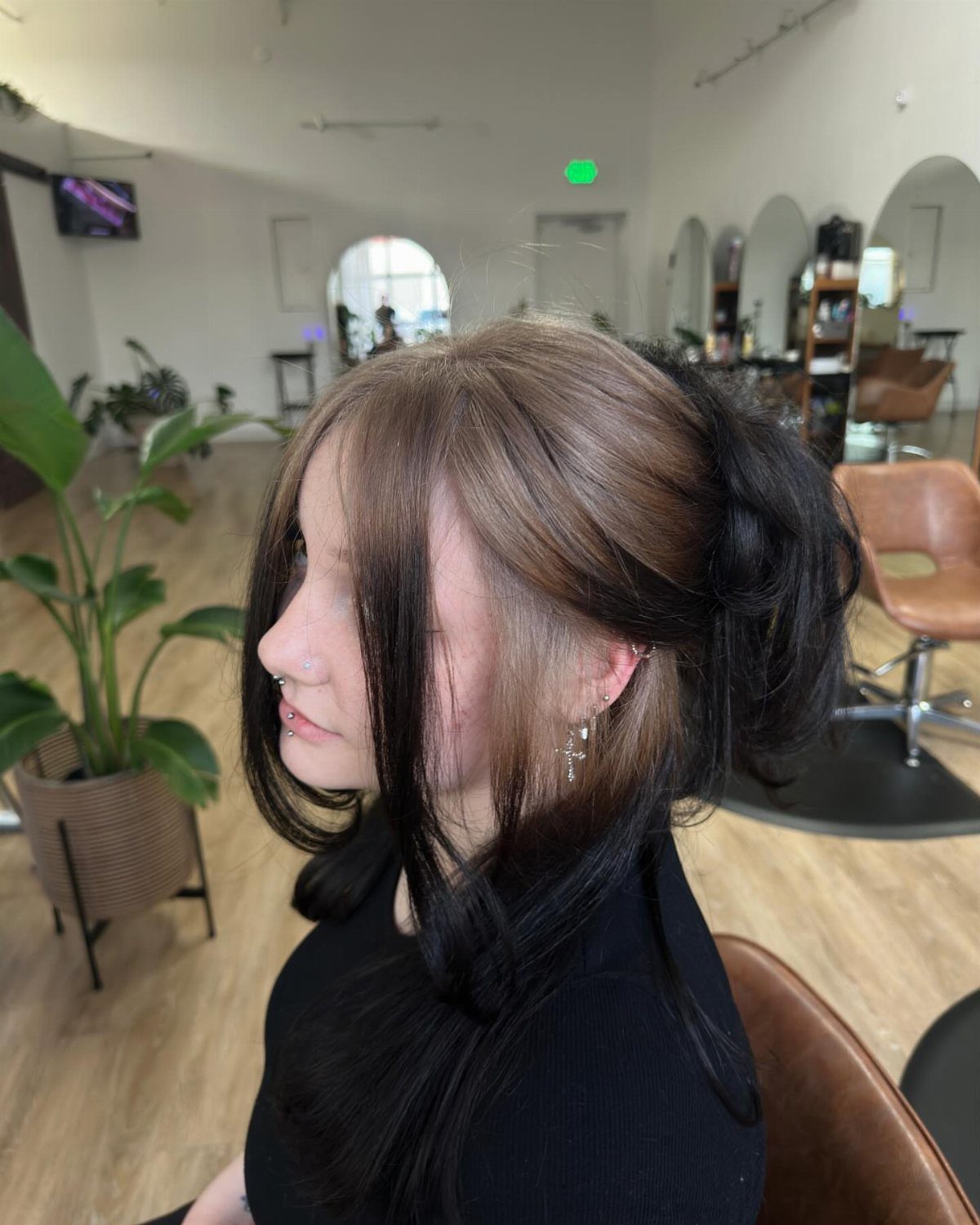 Long dark hair with a broad grown-out light-brown root section in a salon