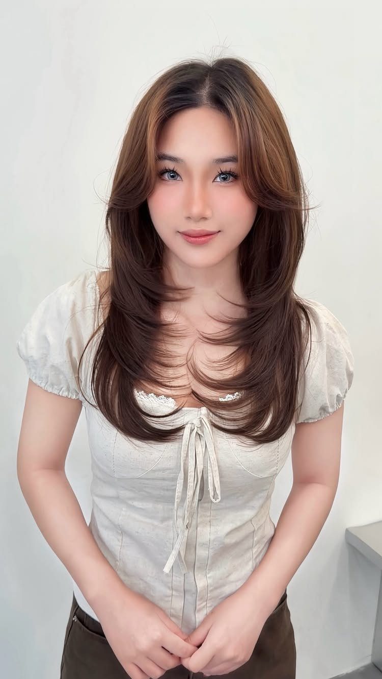 Woman with long chestnut hair styled in soft, blended layers