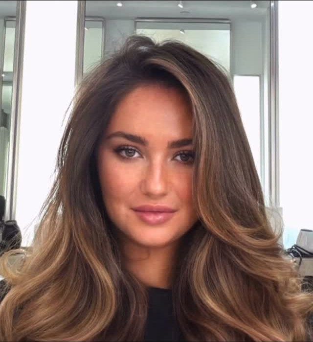 Woman with long, voluminous brown hair showing blended caramel highlights