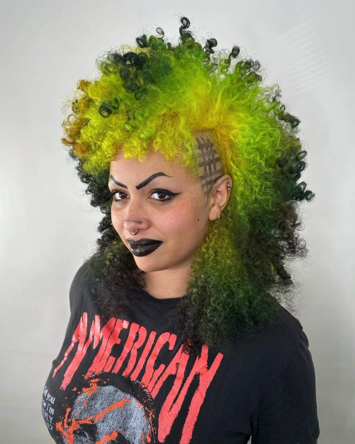 Curly lime-green and yellow hair with dark sides and shaved lines