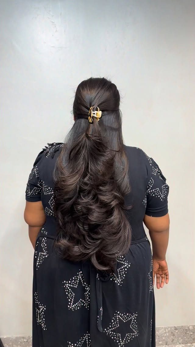 Long dark layered hair cascades in curls down the back