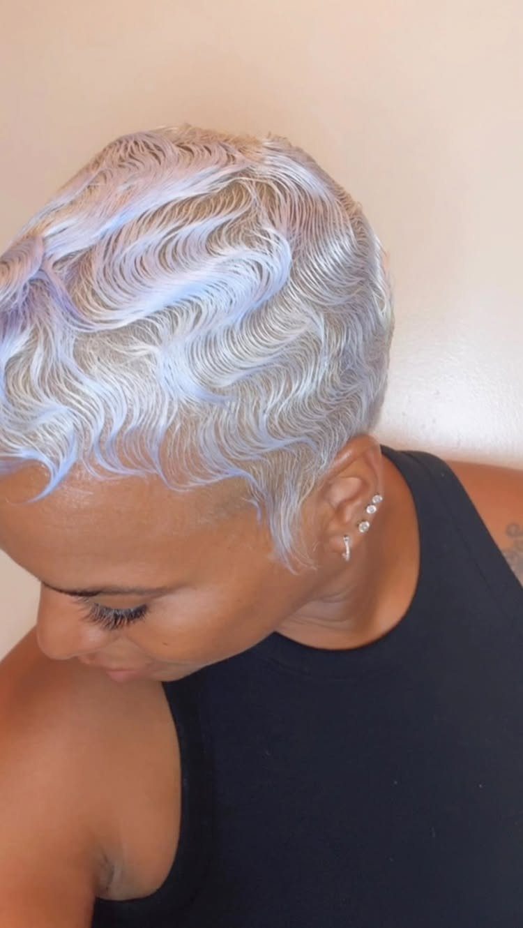 Short platinum-blonde hair styled in soft waves on a person looking down