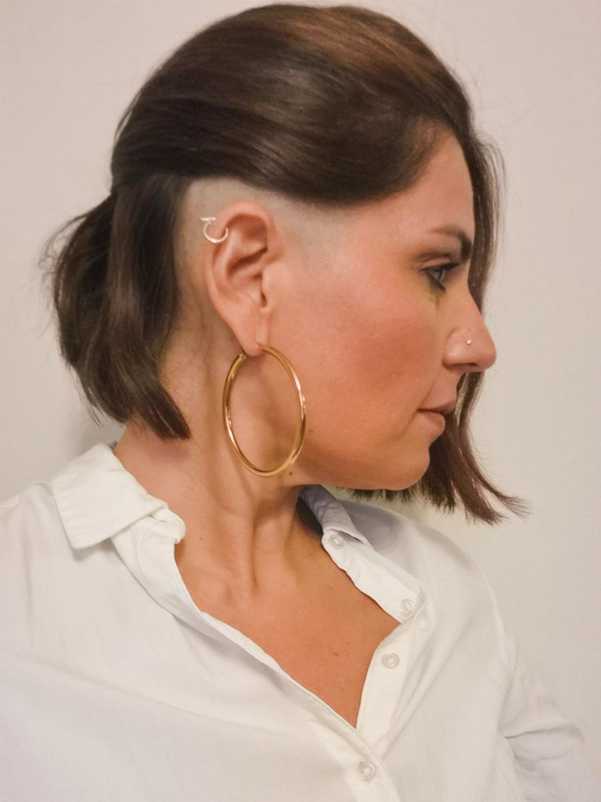Woman with dark brown hair in a short tapered cut, viewed in profile