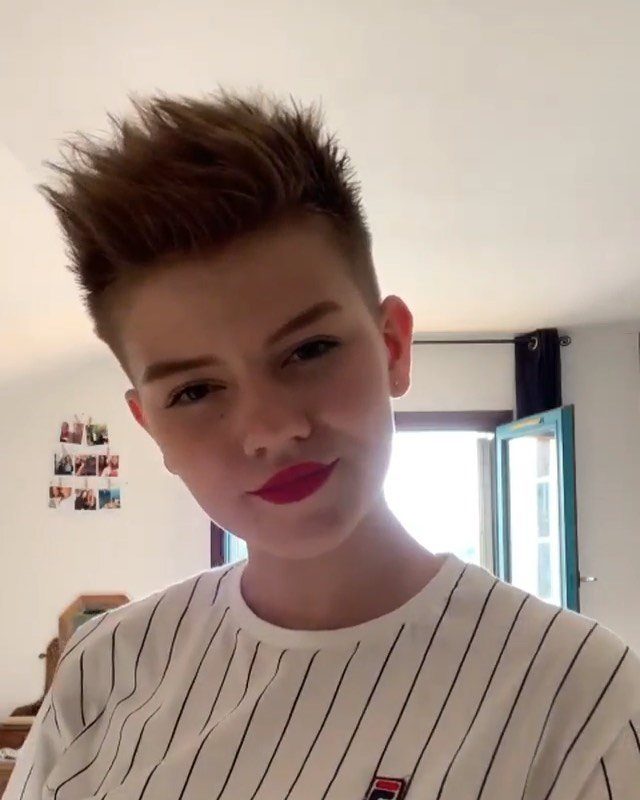 Young person showing a short dark pixie cut styled into upward spikes