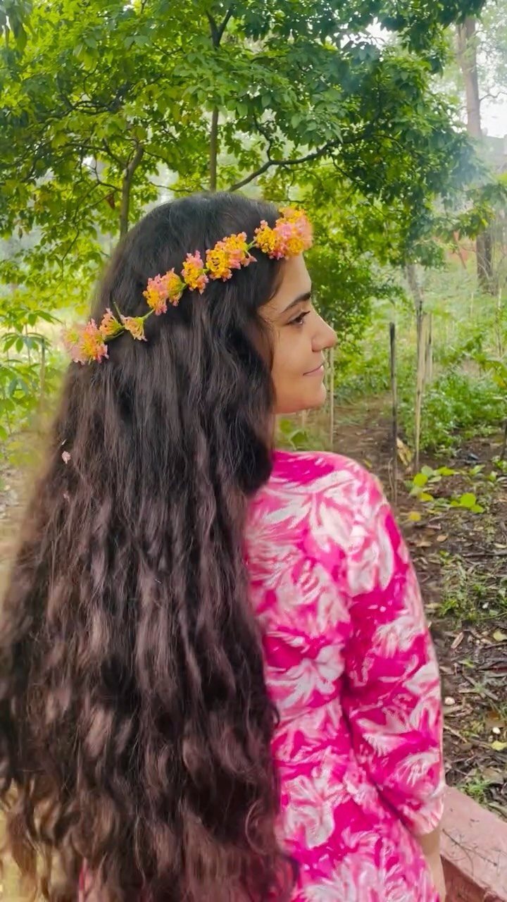 Girl with long wavy hair wearing a colorful flower crown outdoors