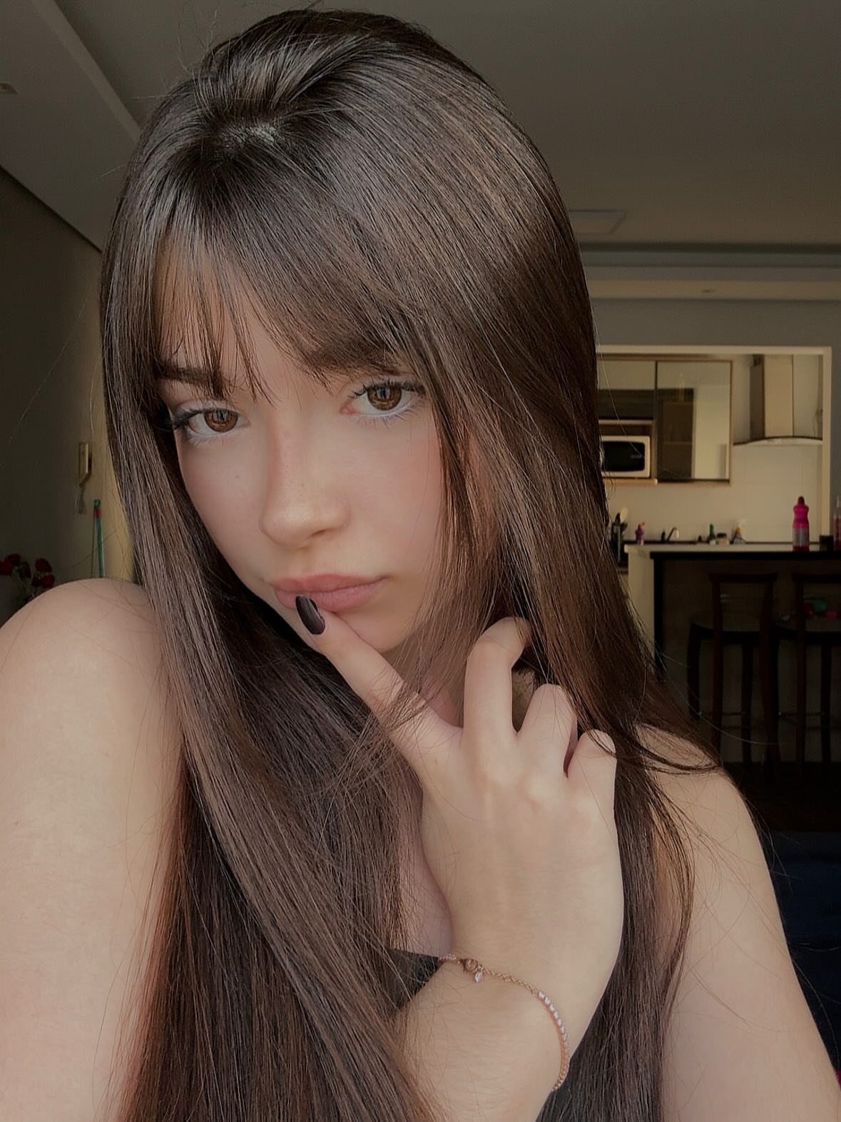 Young woman with long, straight layered brown hair and face-framing bangs