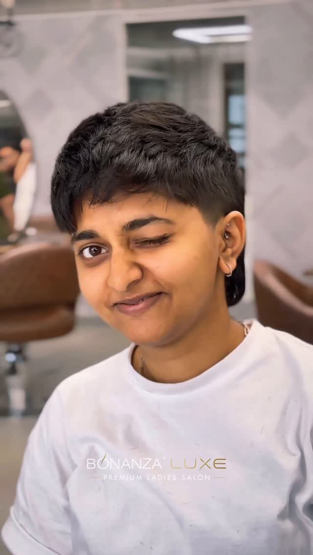 Person showing a short, textured dark pixie cut in a salon chair