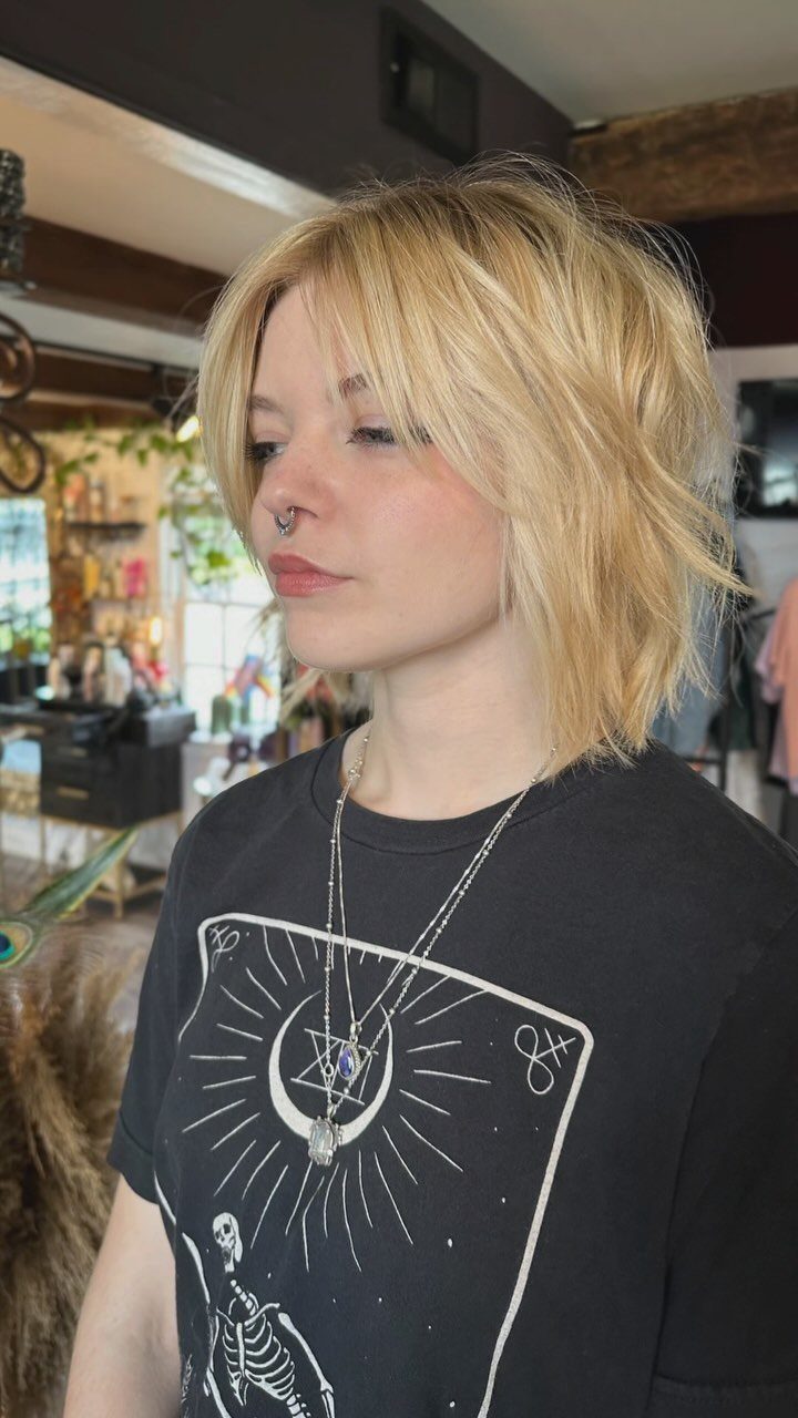 Young person showing a tousled blonde shaggy bob with layered ends