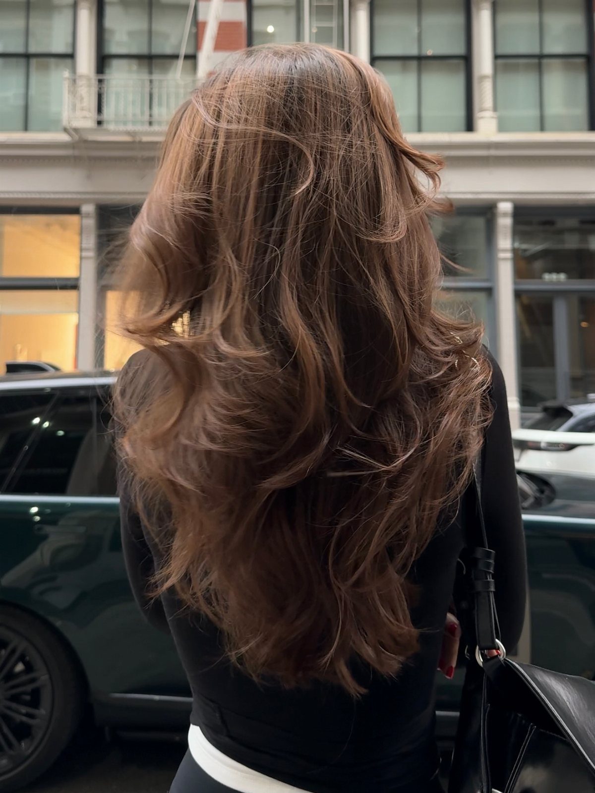 Long brown hair falls in loose, tousled waves down the back