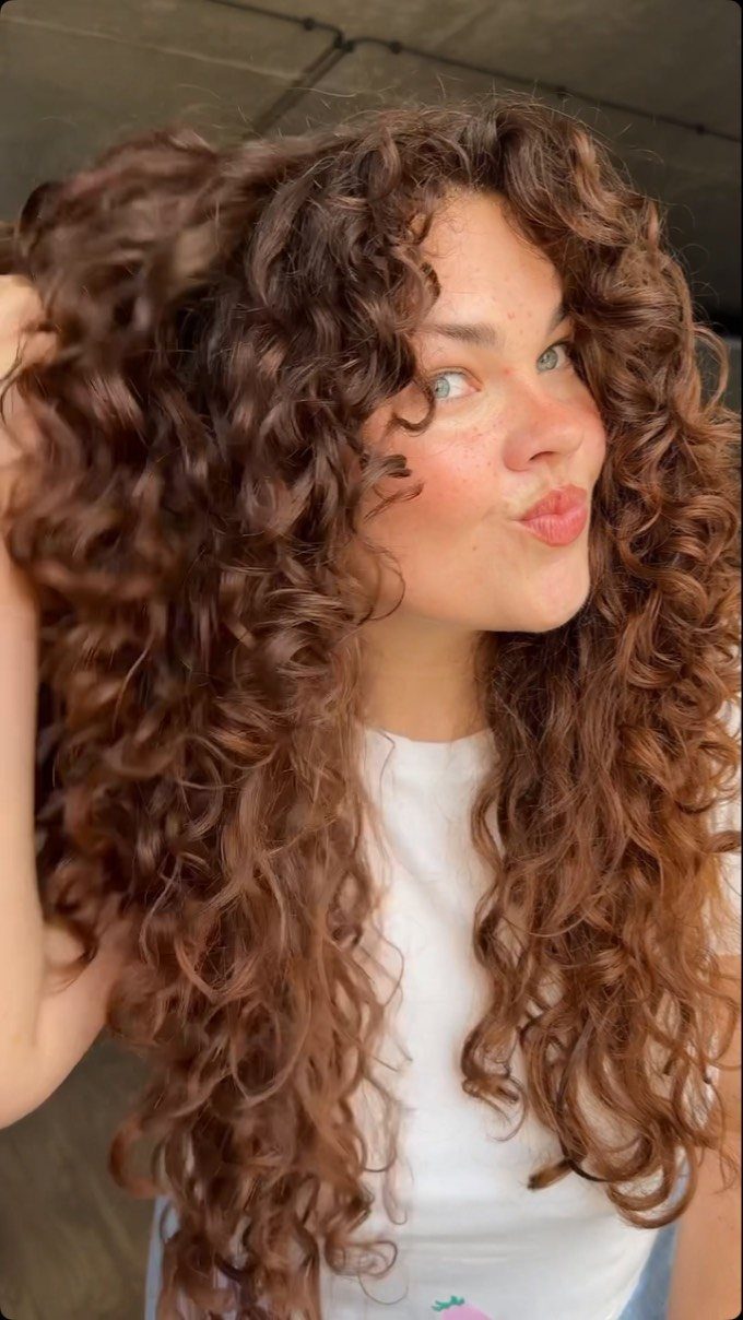 Young woman showing long, voluminous side-parted brown curls