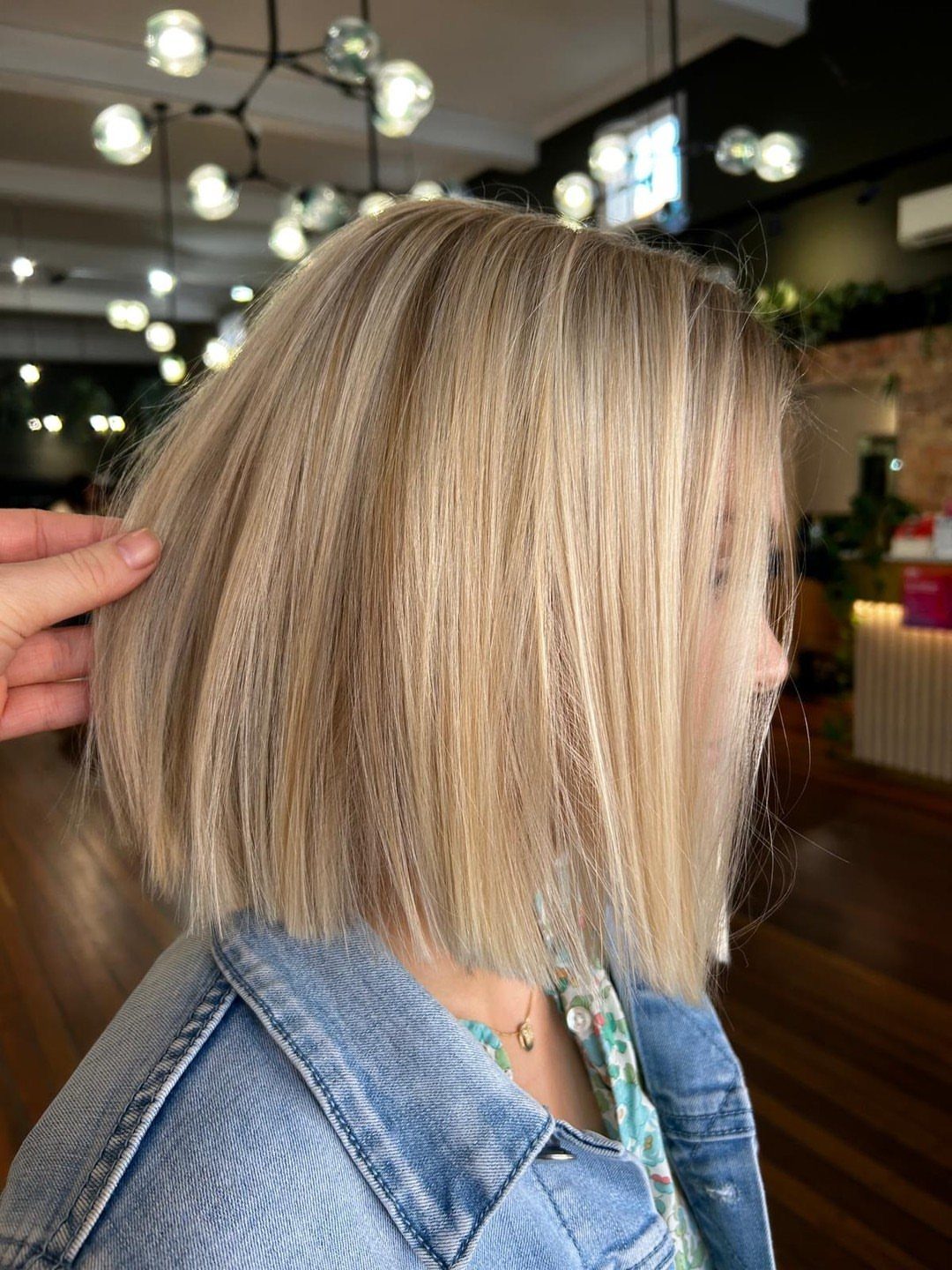 Blonde blunt-cut hair falls straight to the shoulders in a salon