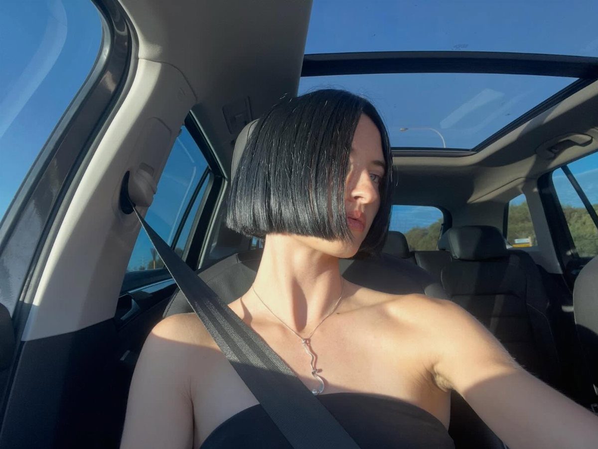 Woman showing a sleek, straight-across chin-length black bob in a car