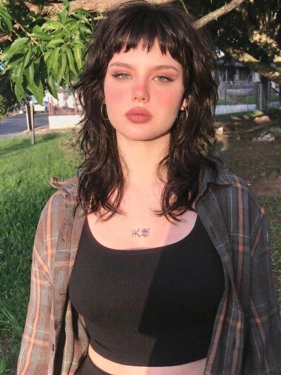Person with a dark disconnected shag, short bangs, and longer tousled layers outdoors
