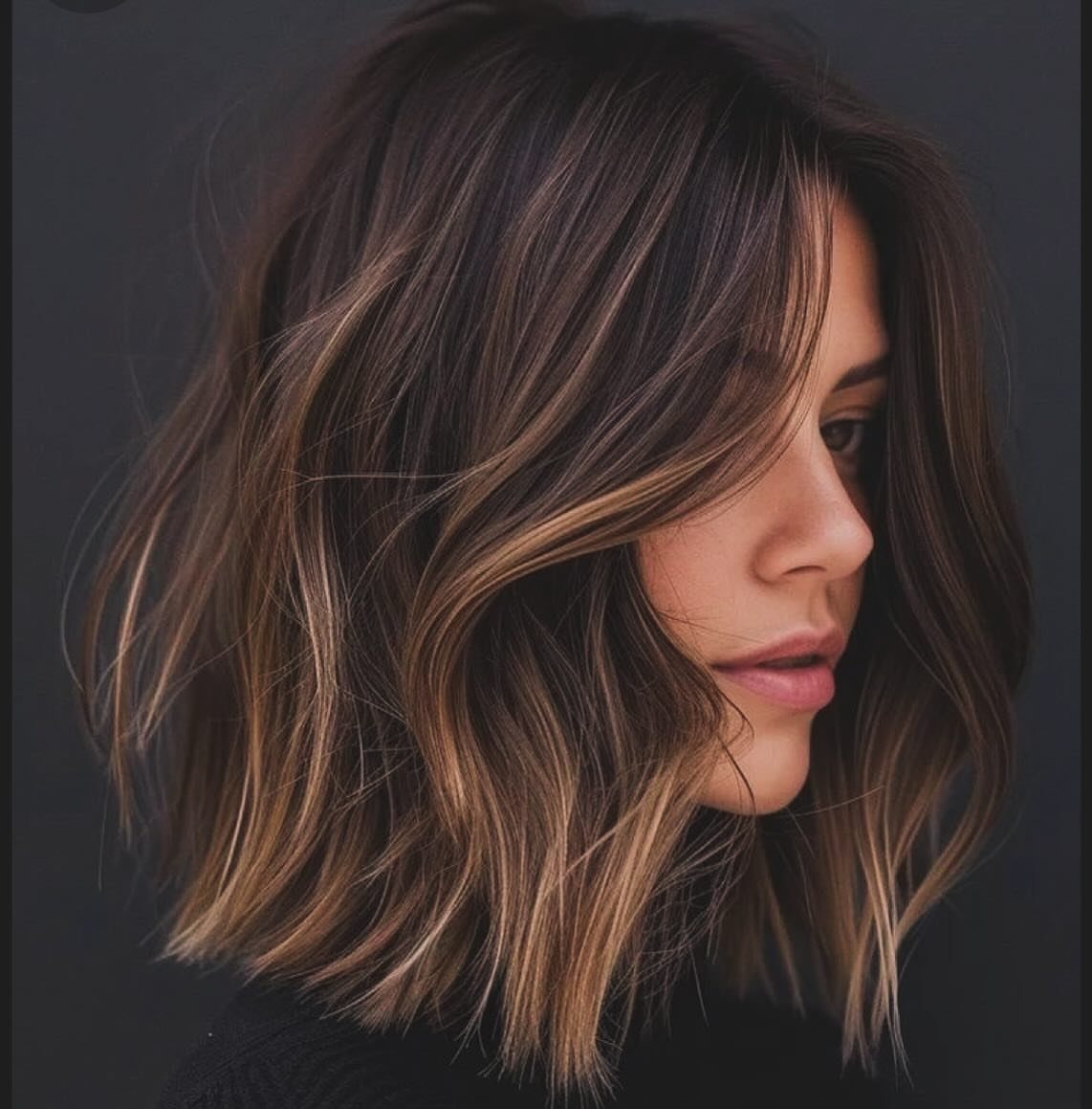 Woman with highlighted, wavy shoulder-length hair in a textured lob