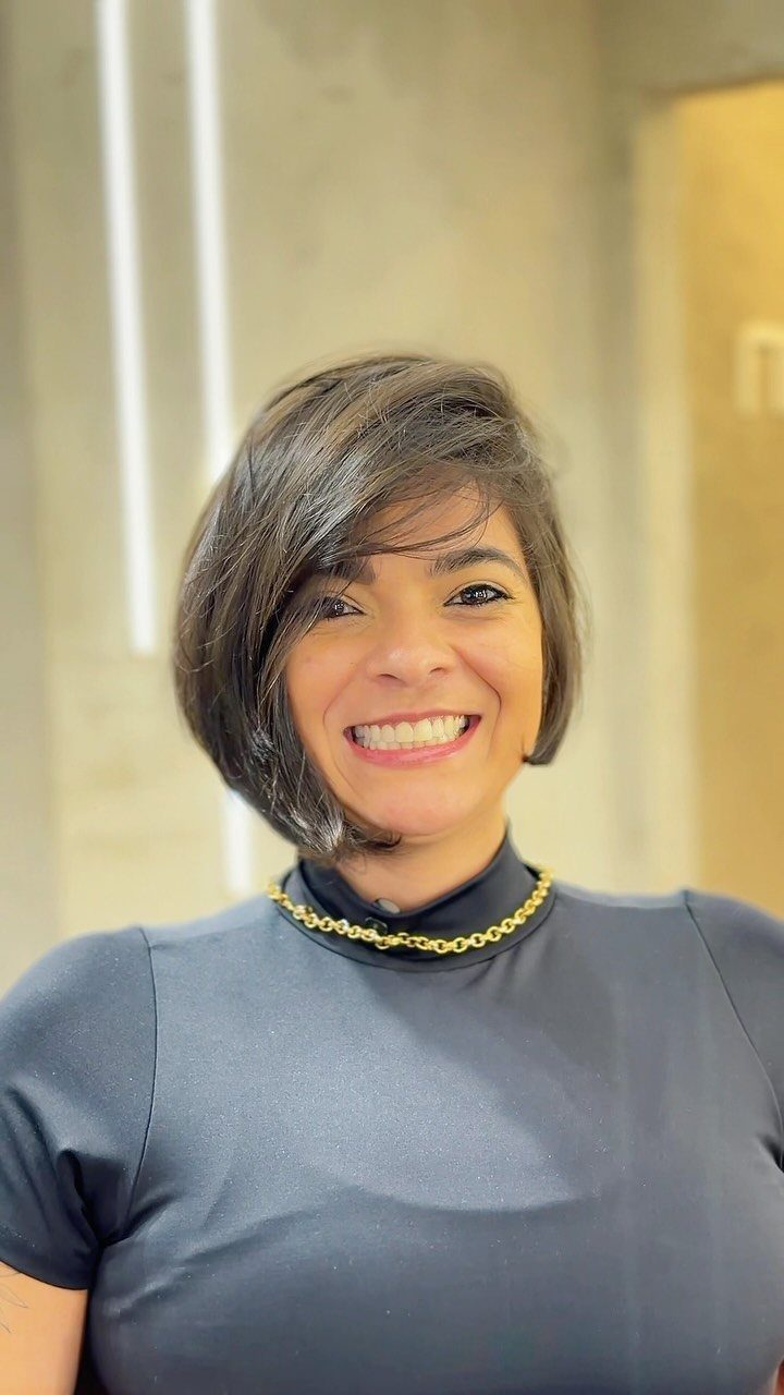 Woman smiling with a side-parted asymmetrical bob and dark top