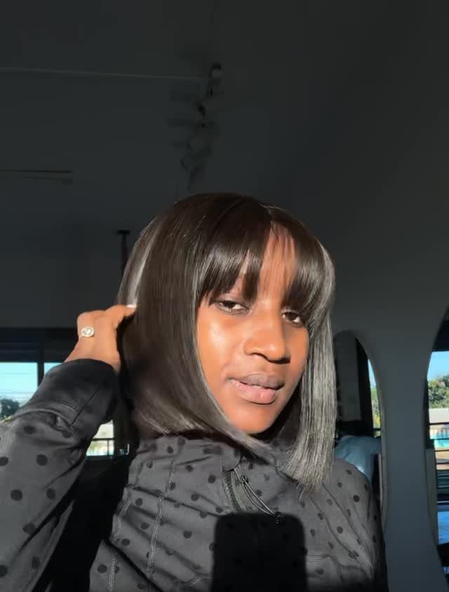 Person showcasing sleek dark bob haircut with straight blunt bangs inside a car