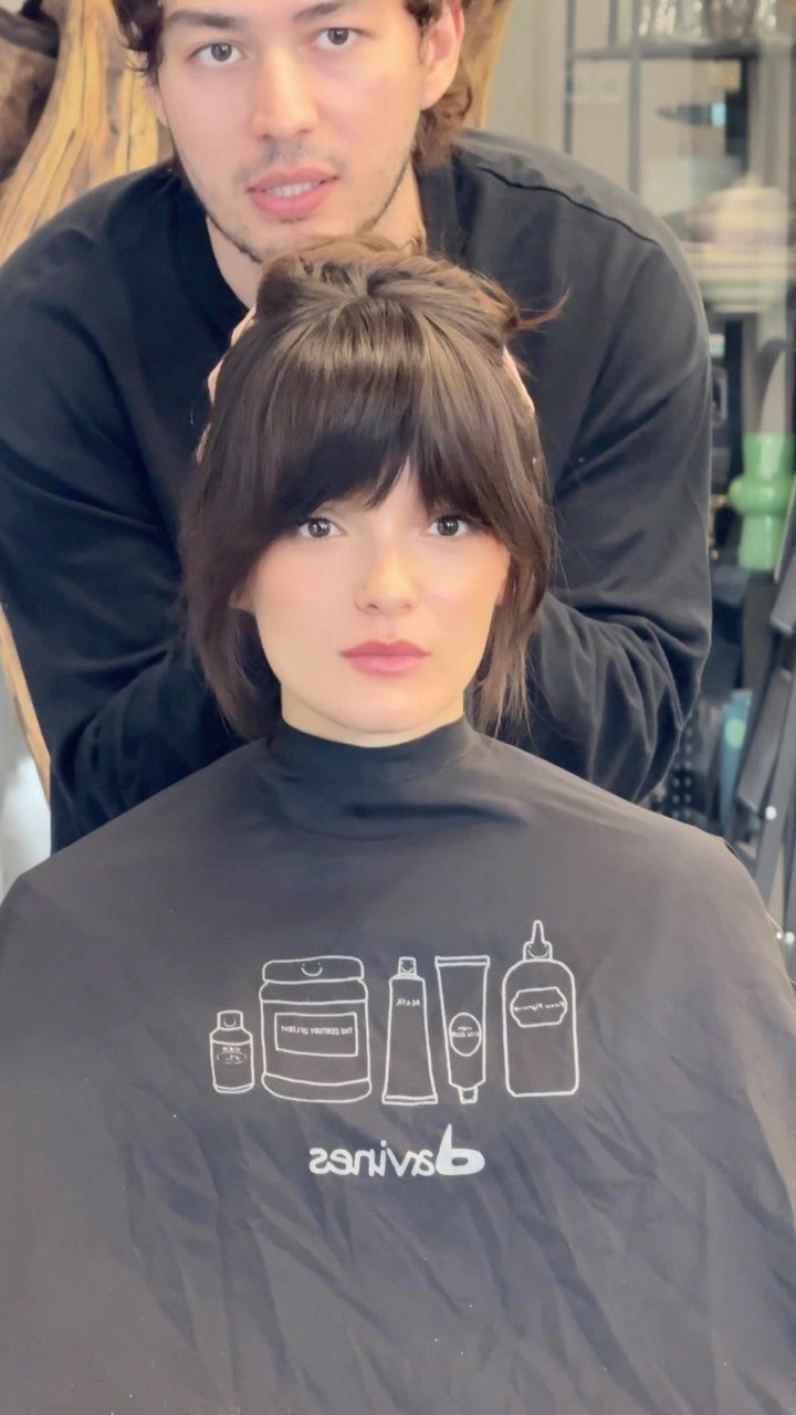 Woman with wispy curtain bangs seated in a salon chair