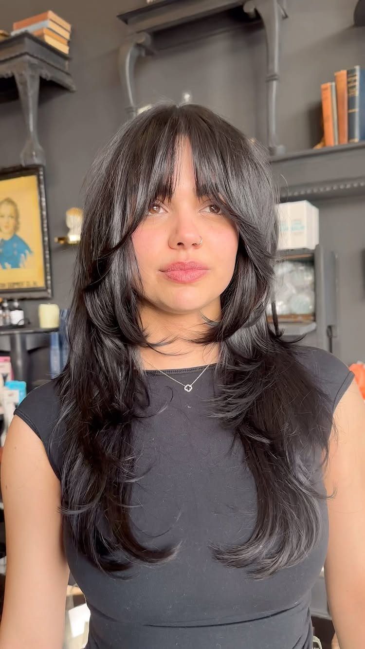 Woman showing long, dark shag layers with full curtain bangs