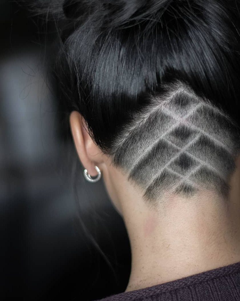 Shaved undercut with intersecting diagonal lines beneath swept-up dark hair