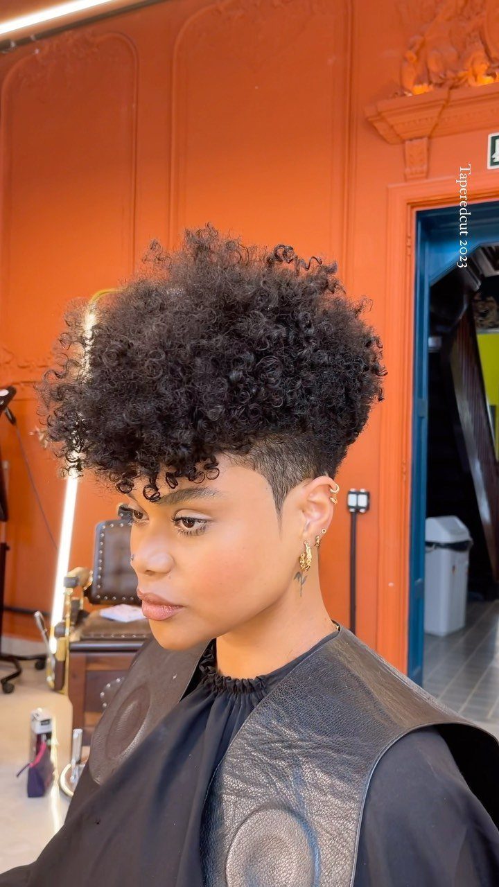 Person with a rounded coily afro and closely clipped sides in a salon