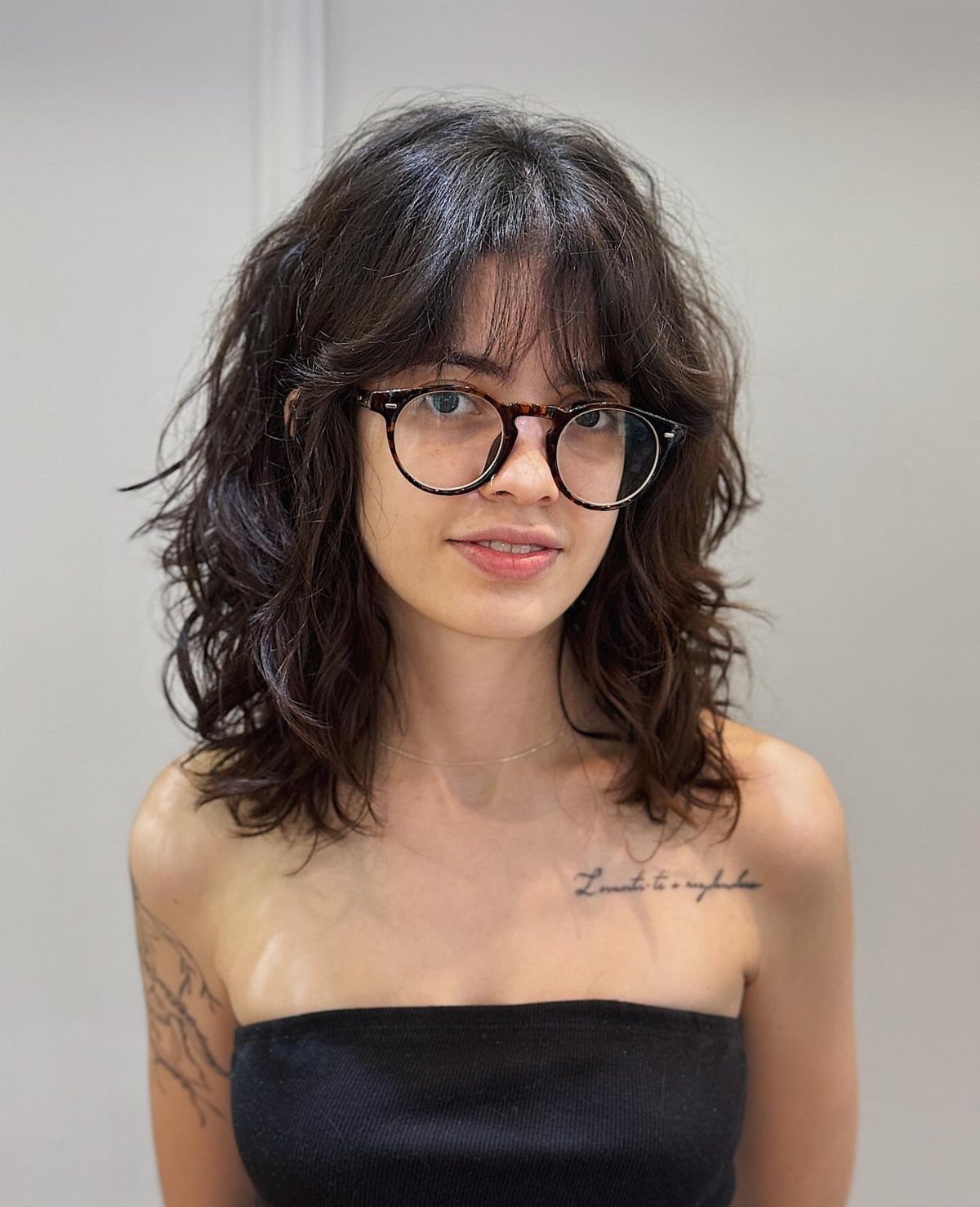 Woman with wavy shoulder-length hair and face-framing layers