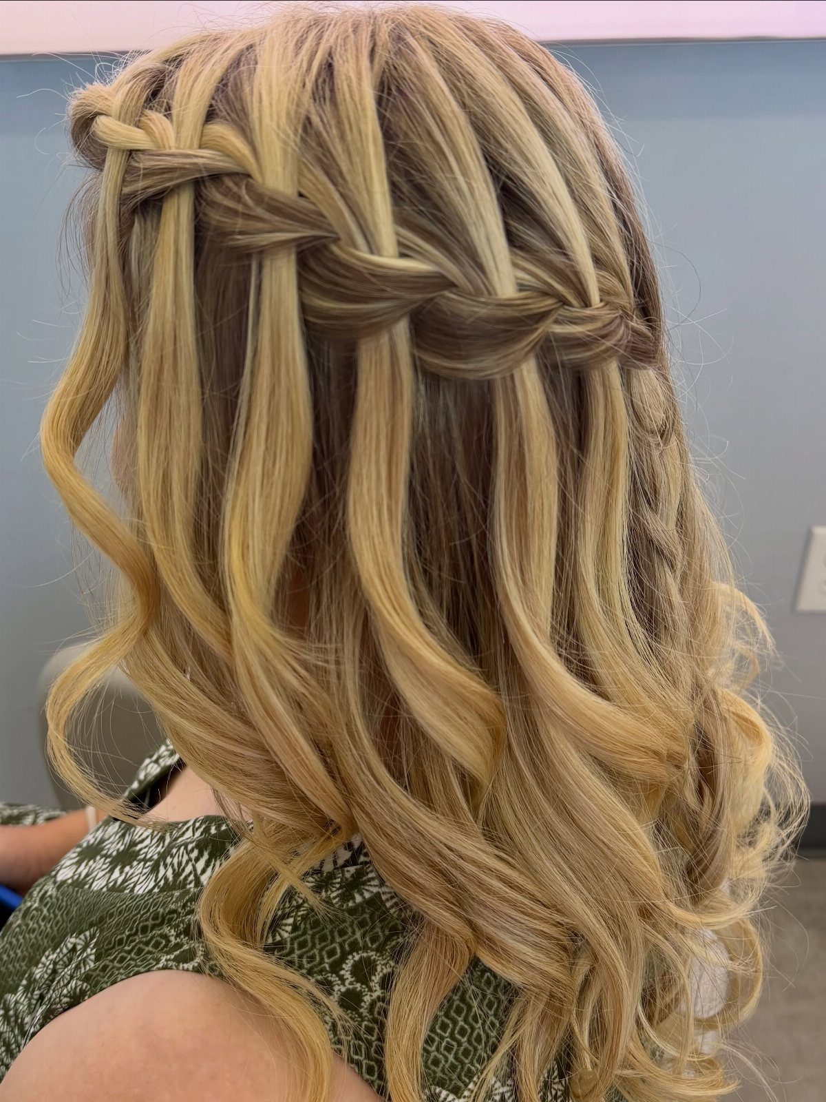 Blonde waterfall braid woven across loose, cascading curls
