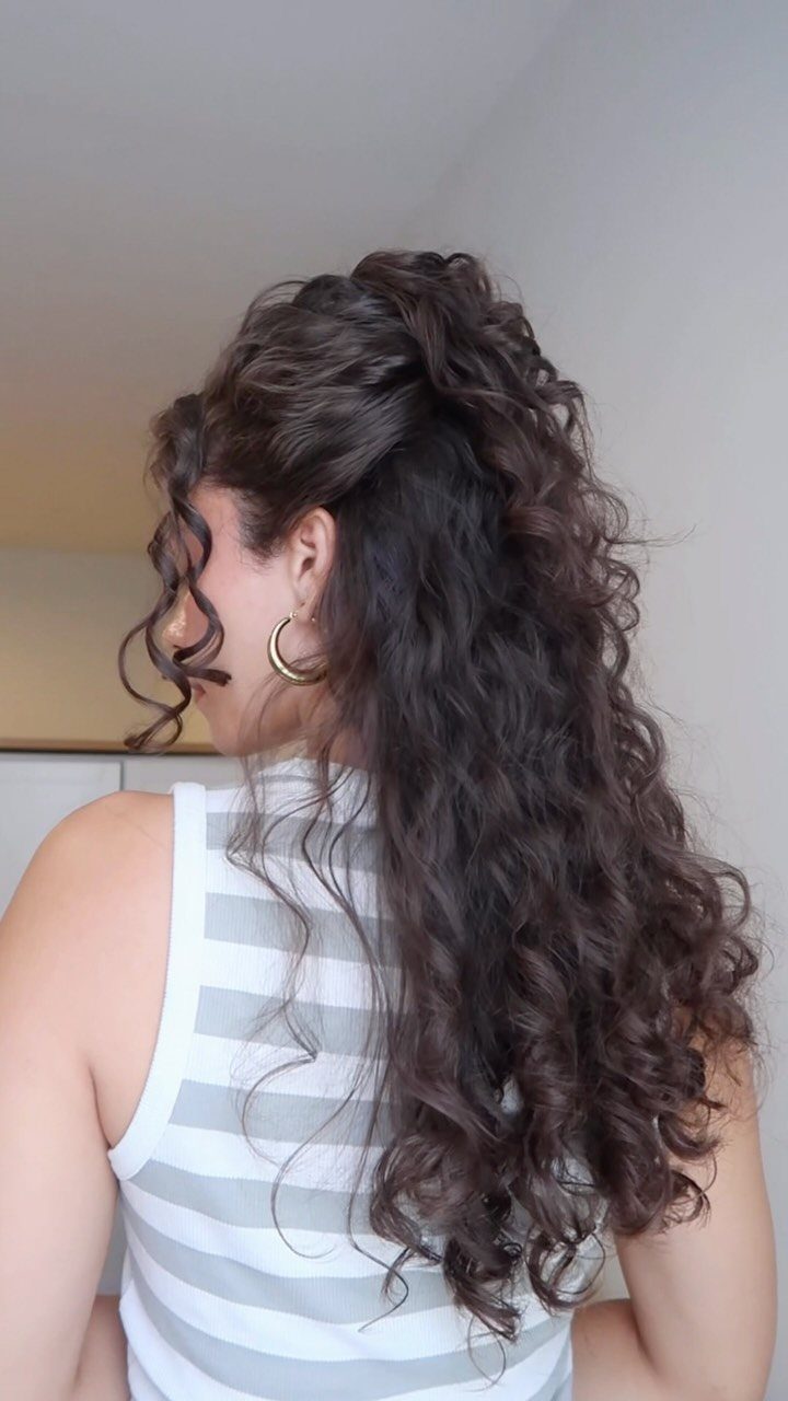 Dark curly half-up hairstyle with a raised crown and face-framing ringlets