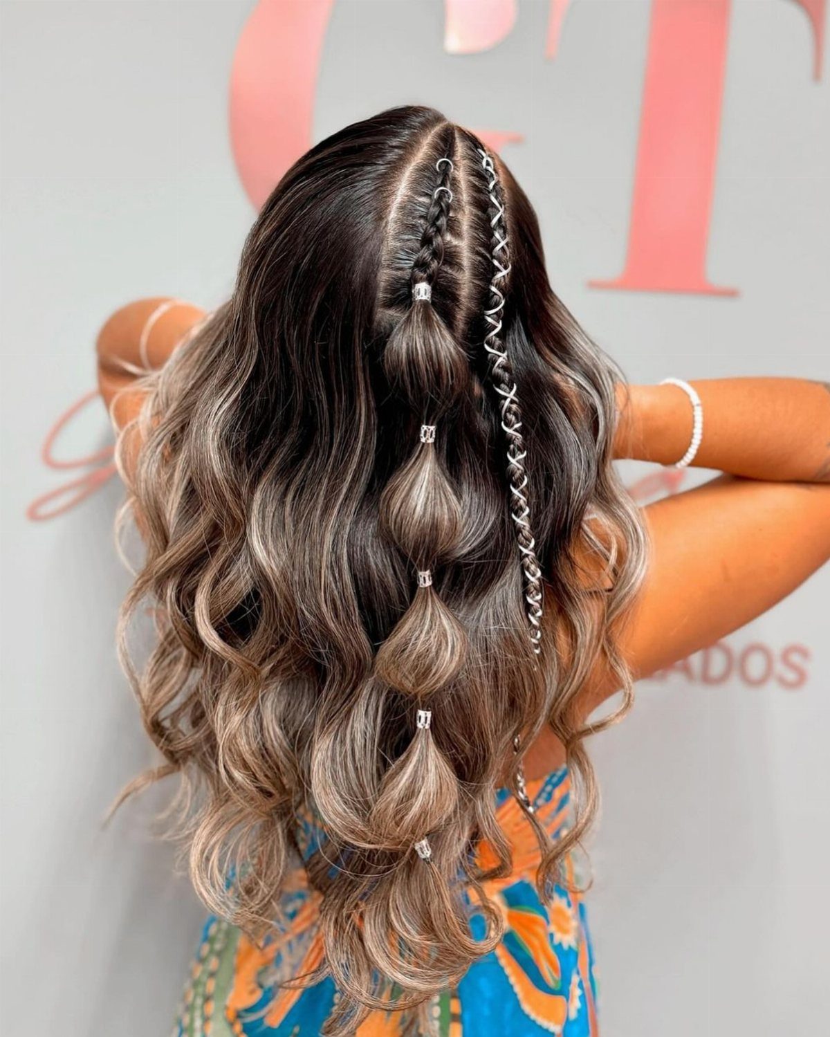 Long wavy hair styled with a fishtail braid and jeweled bubble braid