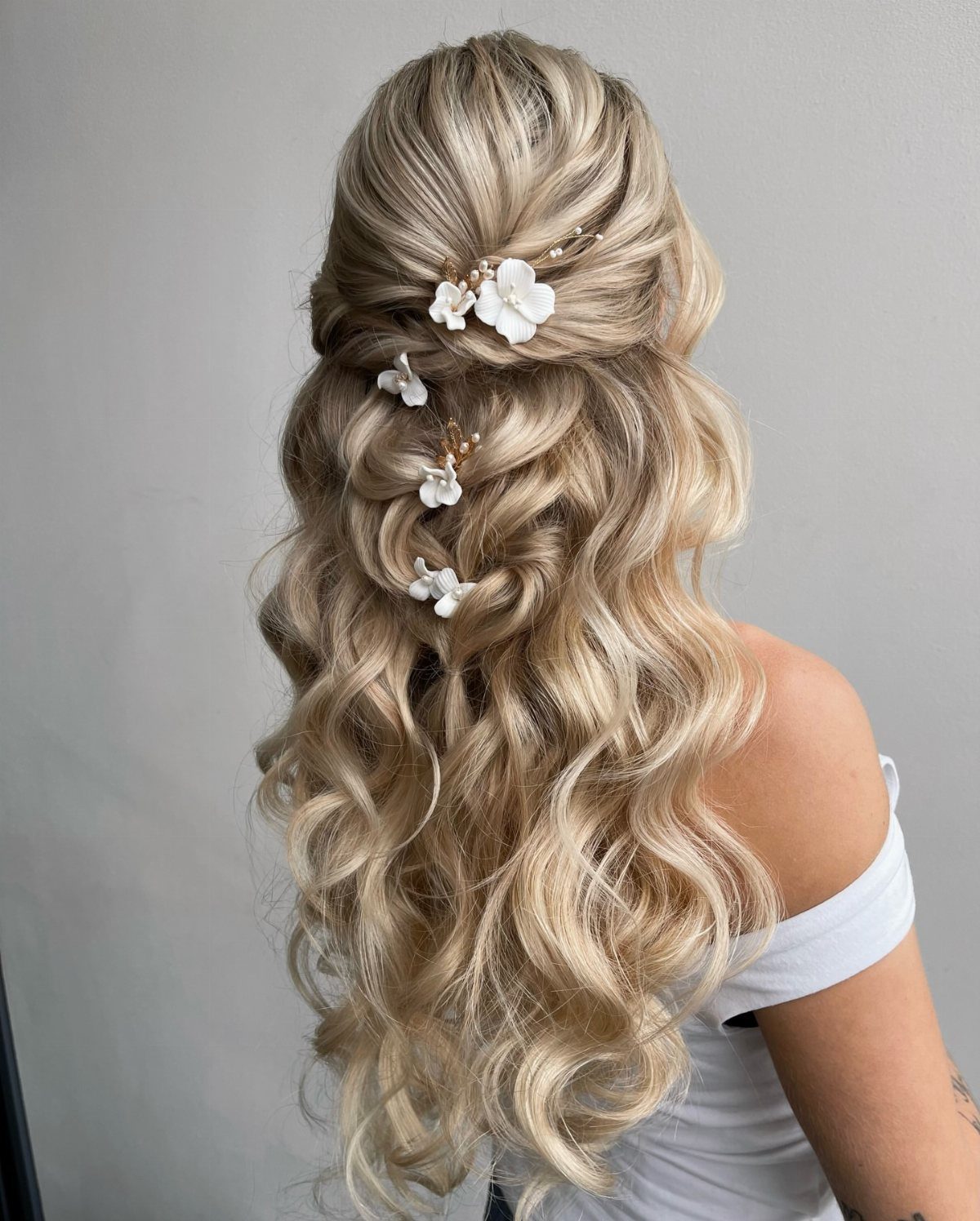 Blonde half-up waves decorated with small white floral hair ornaments
