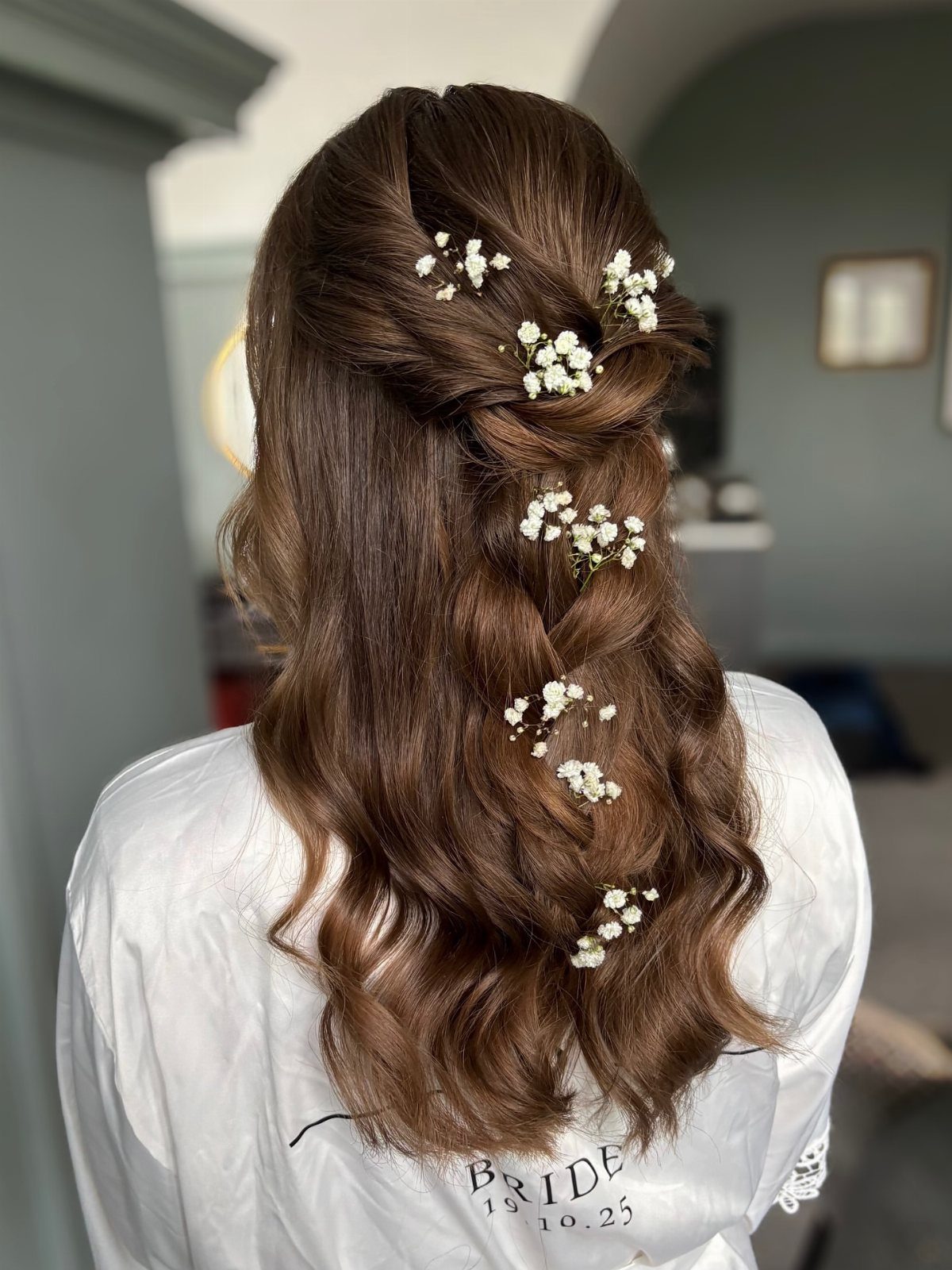 Brown half-up hair with cascading curls and small white flowers