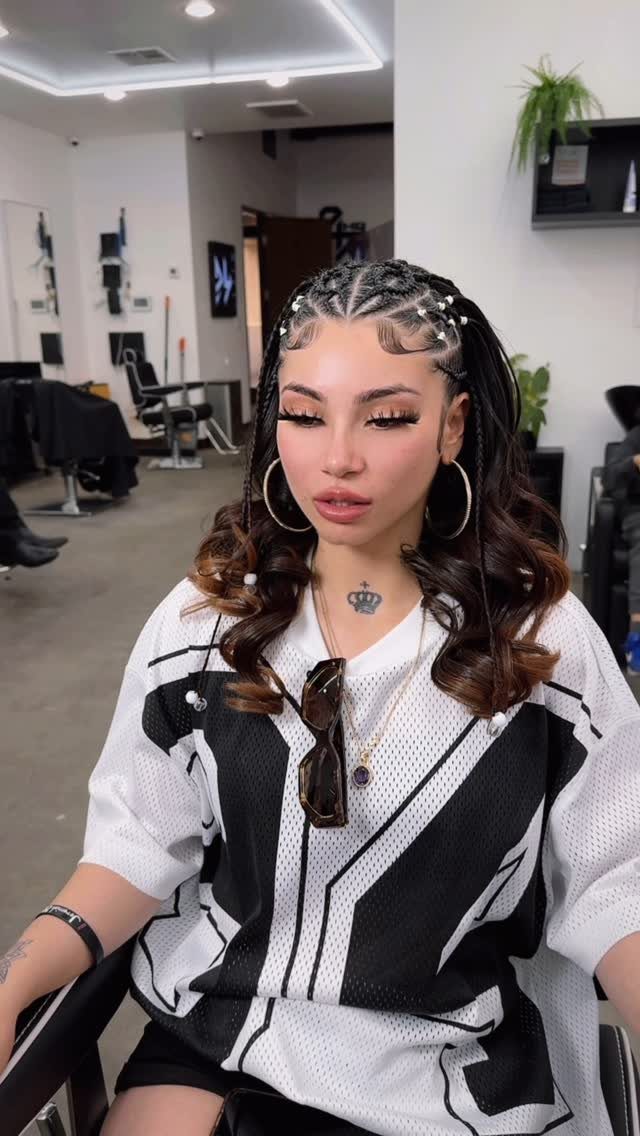 Woman wearing close-fitting crown braids with long loose curls in a salon