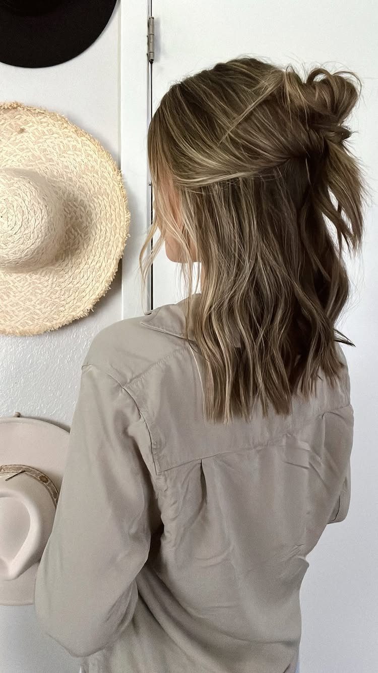 Long highlighted hair styled in a loose knotted half-updo with wavy lengths