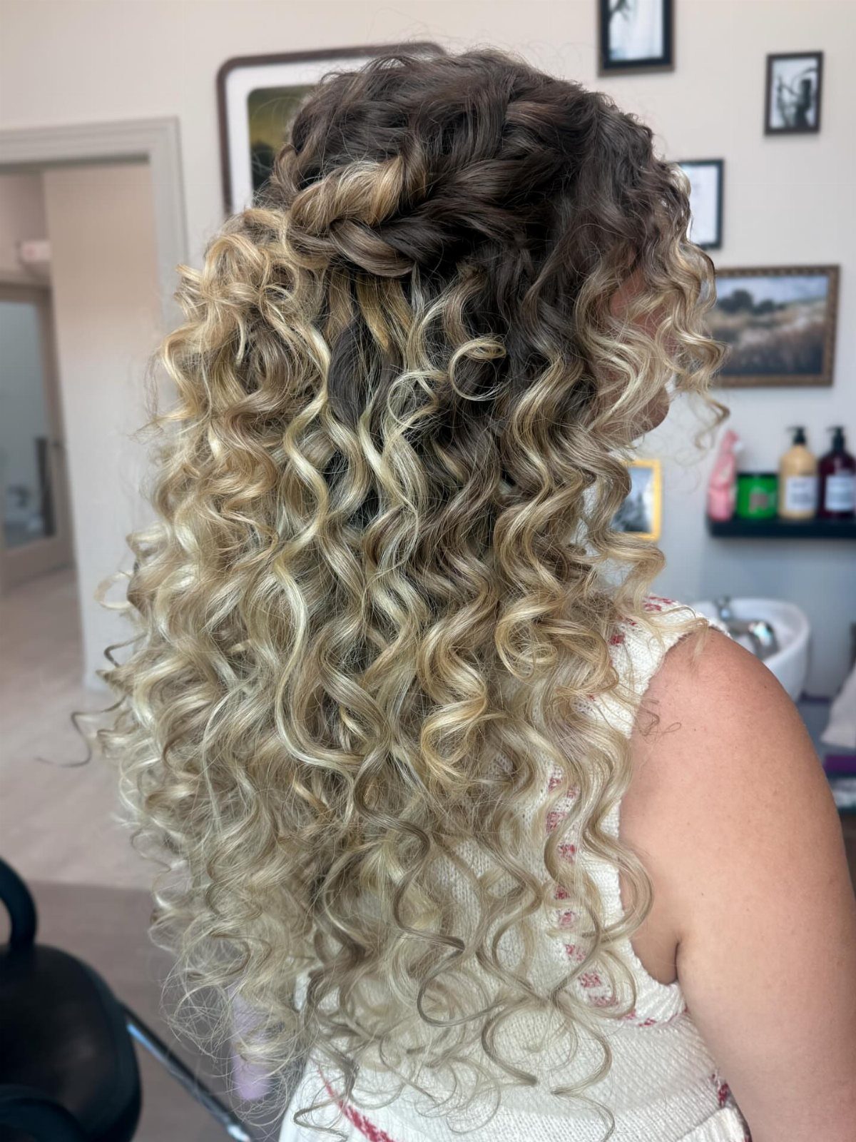 Long blonde curls with dark roots and a braid swept across the crown