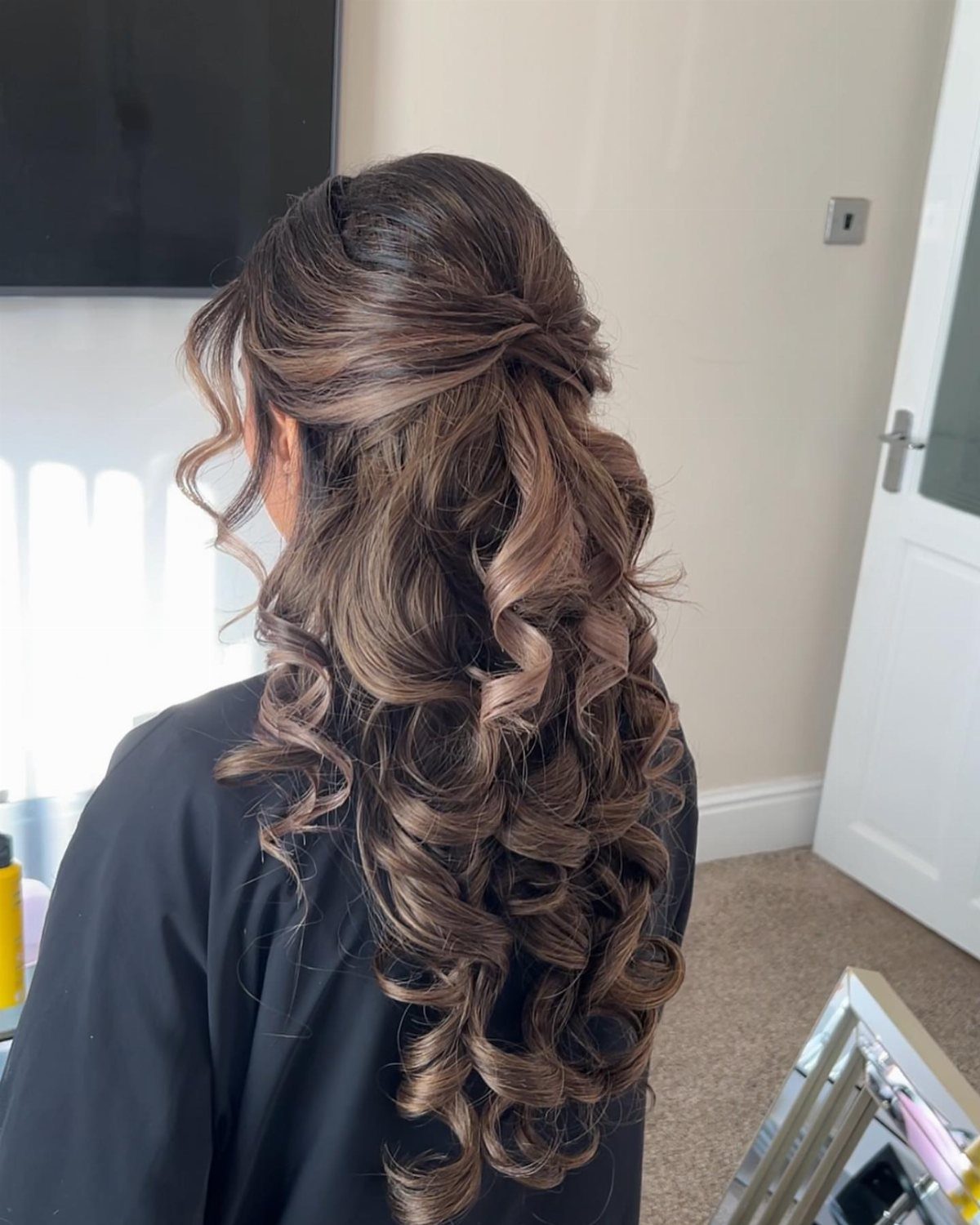 Teased crown with cascading curls styled in a half-up hairstyle