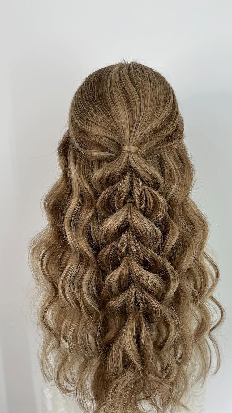 Long blonde waves with a loose, thick fishtail braid in a half-up style