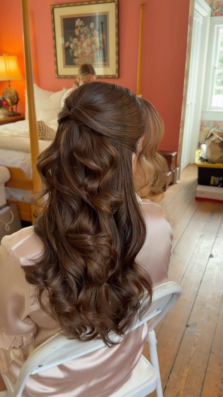Voluminous brown bouffant pinned above long cascading curls on a seated woman