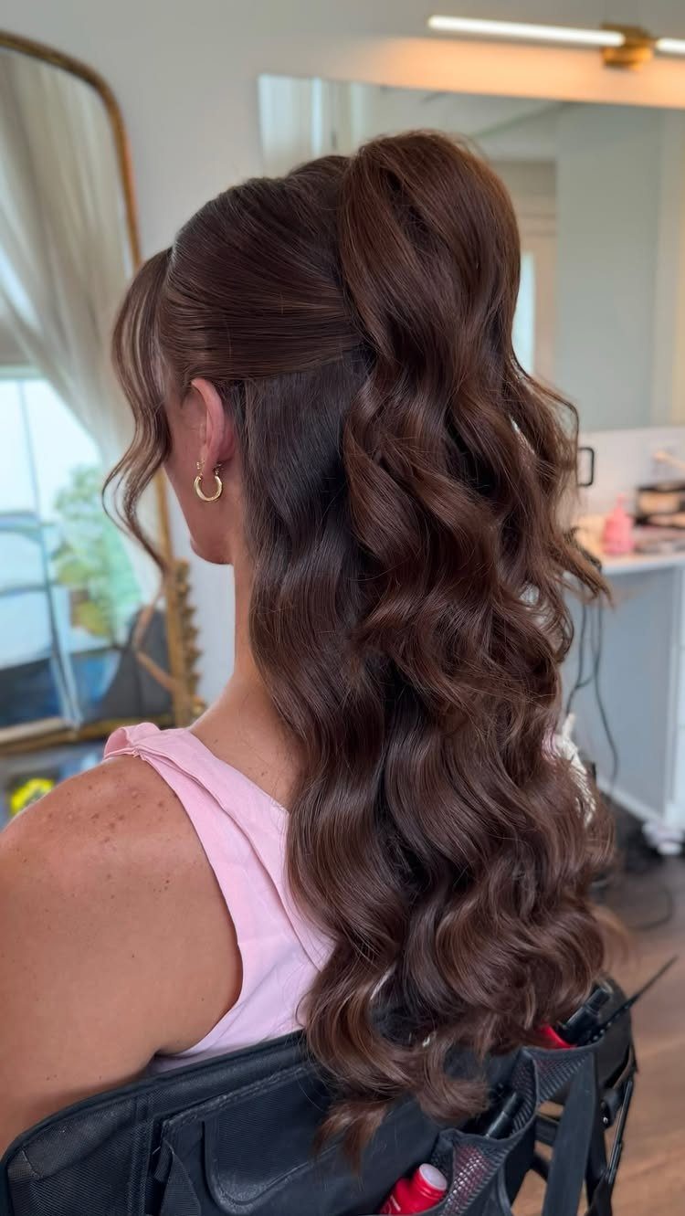 Long dark hair styled half up with a raised crown and curled waves